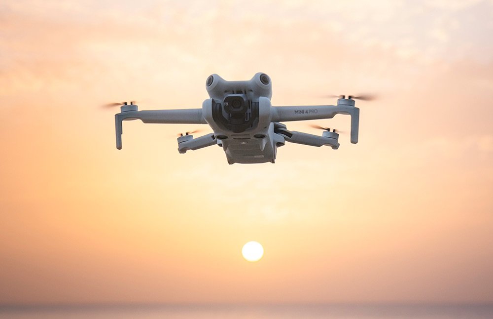 Dron leti u zraku s vidljivim propelerima, snimljen nasuprot zalaska sunca i sunca blizu horizonta—savršena scena za sve koji traže preporuke dronova i žele kupiti dron.