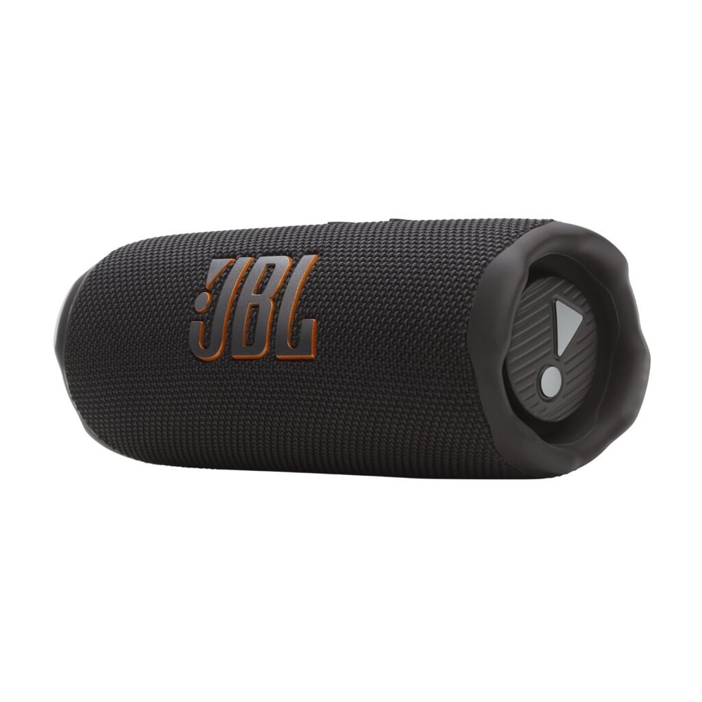 Crni JBL prijenosni Bluetooth zvučnik prikazan je kako leži na boku s vidljivim JBL logotipom i pločom s kontrolnim gumbima na jednom kraju. Predstavljen u naših Top 7 preporuka, idealan je za one koji traže najbolji Bluetooth zvučnik.