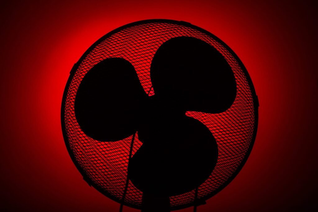 Silueta električnog ventilatora s tri lopatice, gledana sprijeda na crveno osvijetljenoj pozadini - savršen izbor za one koji traže najbolje ventilatore ili žele snažnu preporuku za pouzdane ventilatore.