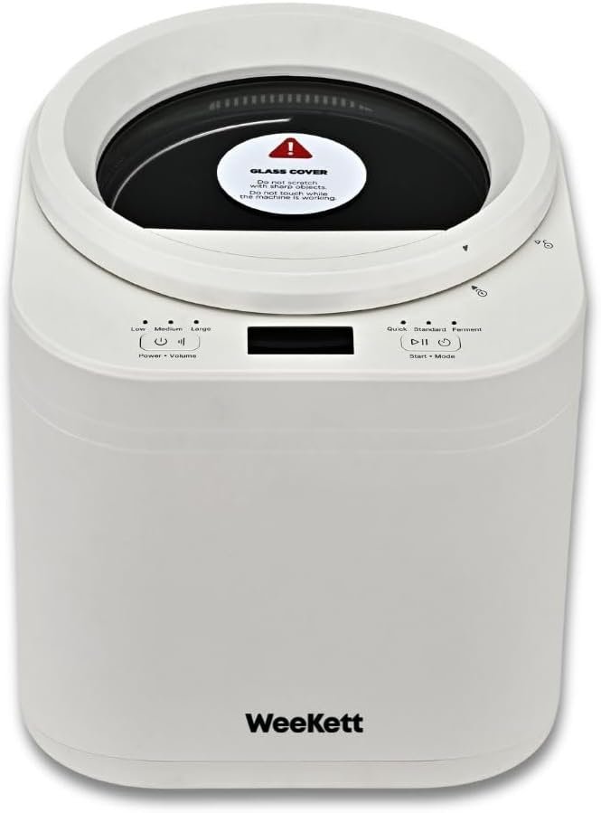 Bijeli WeeKett uređaj s okruglim crnim vrhom, digitalnim zaslonom, gumbima i naljepnicom upozorenja na staklenom poklopcu.